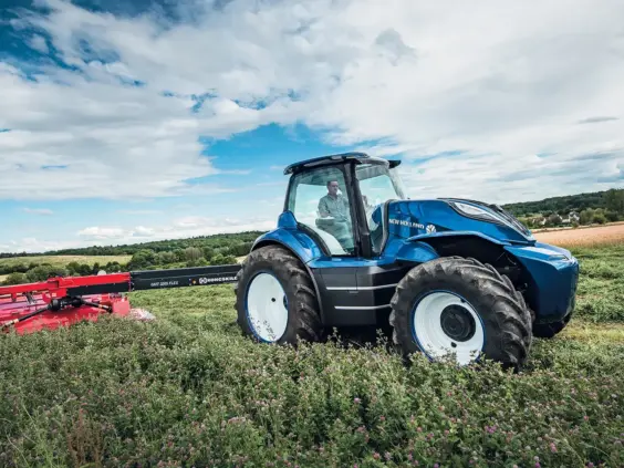 En blå T7.270 Methane Power with PLM Intelligence traktor i arbeid på en grønn eng.