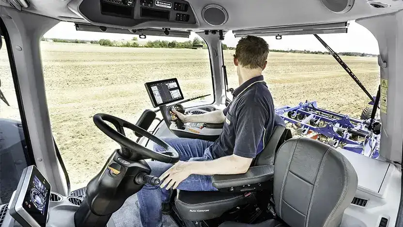 Fører i den moderne hytta på en New Holland T8 Genesis traktor på jordet.
