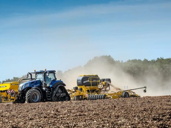 Blå New Holland T8 Genesis traktor som sår på en tørr åker.