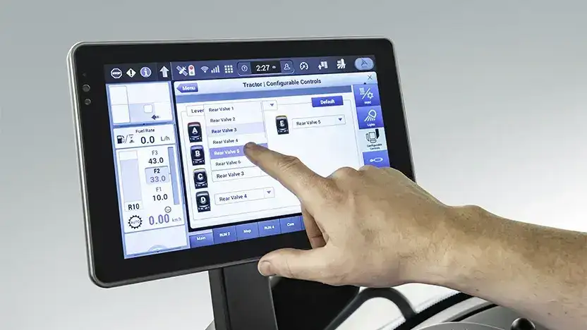 En hånd som berører den digitale kontrollskjermen i en New Holland T8 Genesis traktor.