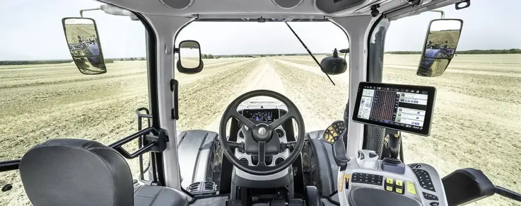 Utsikt fra førerhuset i en New Holland T8 Genesis traktor over et åpent jorde.