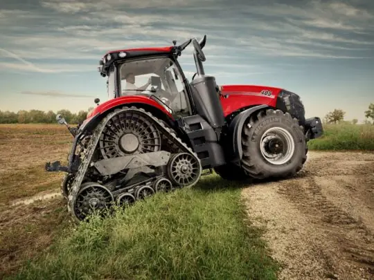 Rød Case IH traktor fra Magnum-serien med belter på et jorde under skyet himmel.