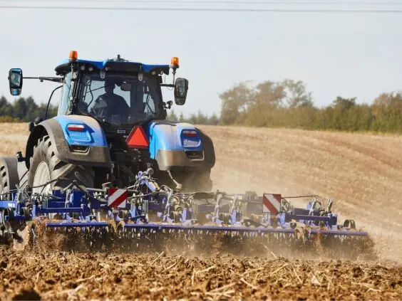 Blå traktor i arbeid på en åker med DALBO Trimax Lift stubbkultivator.