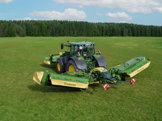 Grønn traktor på en eng utstyrt med en KRONE EasyCut B slåmaskin.
