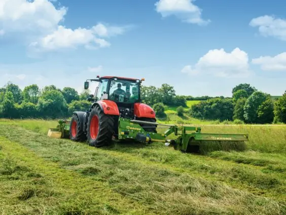 Rød traktor som slår gress med en Krone EasyCut R slåmaskin.