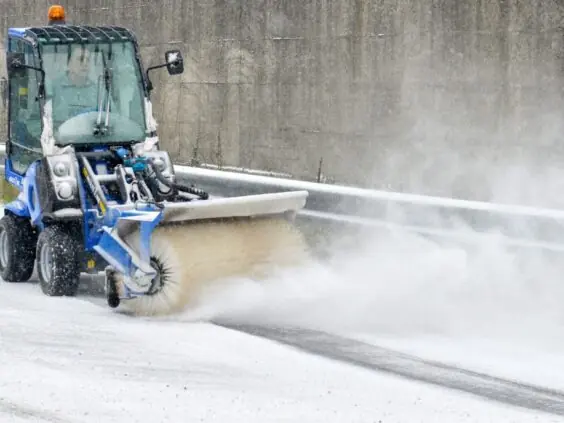 MultiOne 2.3 minilaster med feiebørste rydder snø effektivt på en vintervei.
