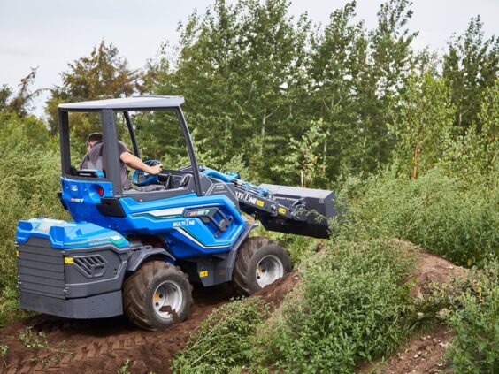 Blå MultiOne EZ-serie elektrisk kompaktlaster i arbeid på en jordhaug ute.