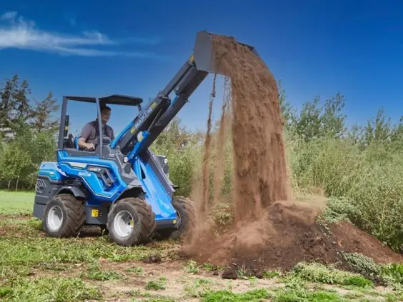 En MultiOne EZ-serie elektrisk kompaktlaster som tipper jord på en haug utendørs.