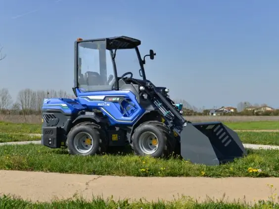 Blå MultiOne EZ-serie elektrisk kompaktlaster parkert på gress med en grå skuffe.