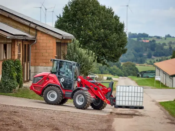 Rød Weidemann Hjullaster 4060 som transporterer en hvit IBC-beholder på en gårdsvei.