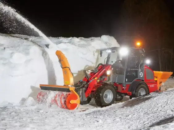 En rød Weidemann Hjullaster 2080 i arbeid med snøfreser om natten.