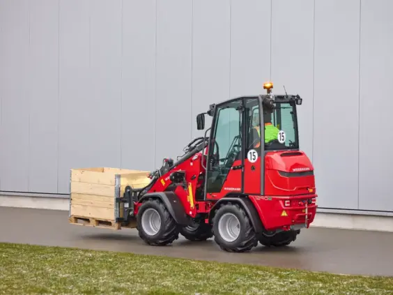 Rød Weidemann Hoftrac 1290e elektrisk minilaster som transporterer en trekasse på en pall.