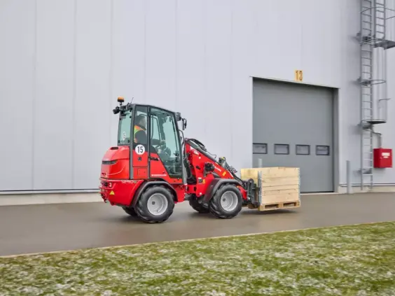 Rød Weidemann Hoftrac 1290e elektrisk minilaster som frakter en pallekasse utendørs.
