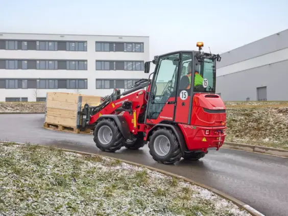 Rød Weidemann Hoftrac 1290e elektrisk minilaster frakter en trekasse utendørs.