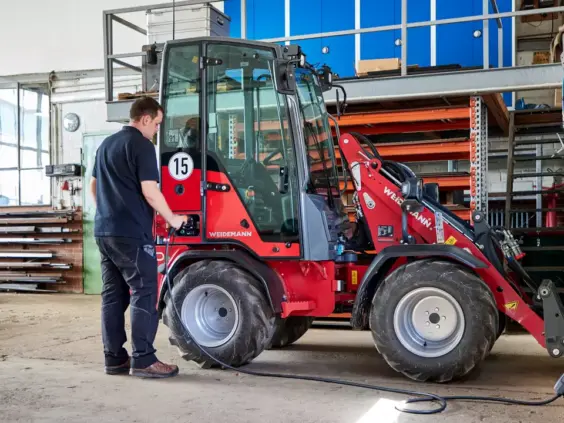 En mann som lader en Weidemann Hoftrac 1190e minilaster i et verksted.