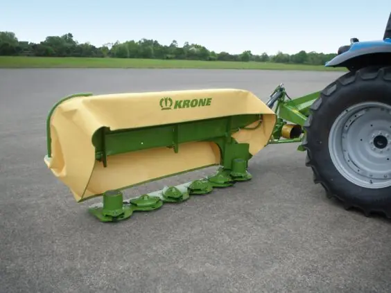 Krone ActiveMow slåmaskin med gult deksel montert bak på en blå traktor.