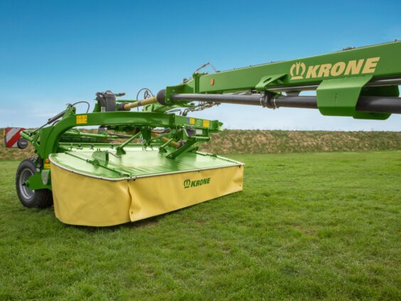 En grønn og gul KRONE EasyCut TS/TC slåmaskin på en grønn gressplen.