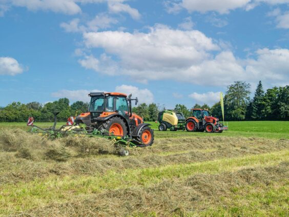 En oransje traktor som bruker en KRONE Vendro sprederive på et jorde.