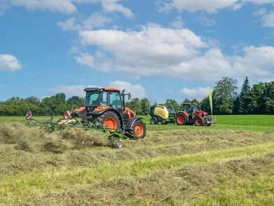 En oransje traktor som bruker en KRONE Vendro sprederive på et jorde.