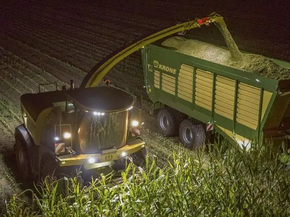 KRONE BiG X 480-630 høster mais om natten og fyller en vogn.