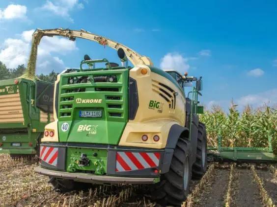 En KRONE BiG X 680-1180 fôrhøster i sving med å høste mais på et jorde.