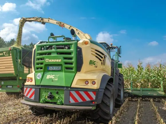 En KRONE BiG X 680-1180 fôrhøster i sving med å høste mais på et jorde.