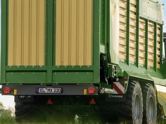 Bakfra-bilde av en grønn og gul KRONE MX lessevogn på en grønn mark.