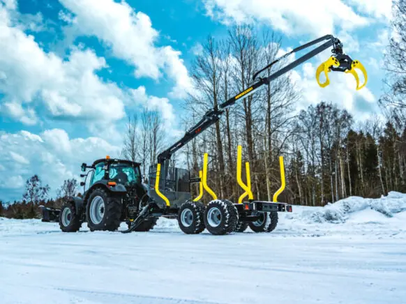 En traktor med Palms 5.87z tømmerkran i et snødekket vinterlandskap.