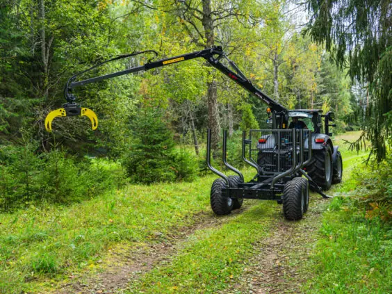 Traktor med Palms 5.87z skogskran og tømmertilhenger på en grønn skogsvei.