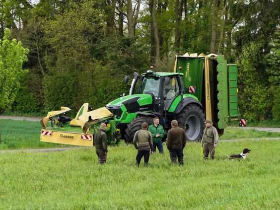En Deutz-Fahr traktor utstyrt med KRONE EasyCut B slåmaskin på et grønt jorde.