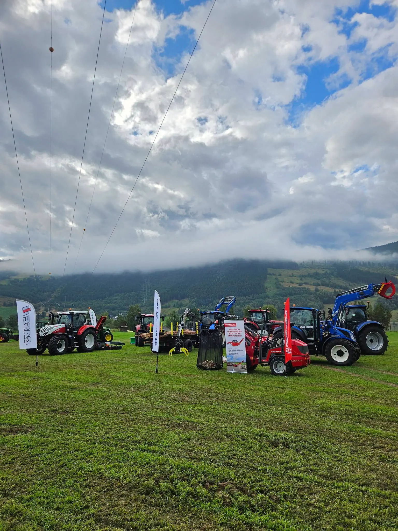 Oversikt over standen til Fron Traktor Service under Traktorrock, med traktorer, tømmervogn og Weidemann hjullaster.