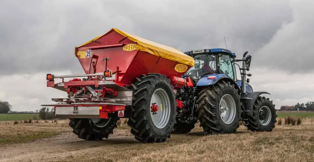 Traktor med enkeltakslet Bredal kalkspreder i arbeid