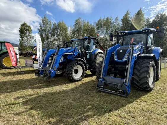 To blå New Holland-traktorer med frontlaster på standen til Fron Traktor Service under Bygdedagene på Dokka.