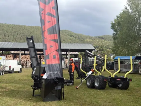 Vedmaskin med transportbånd og PALMS tømmervogn med skogskran på standen til Fron Traktor Service under Bygdedagene på Dokka.