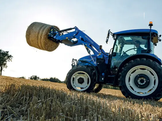 New Holland T5S løfter rundball med frontlaster på stubbåker