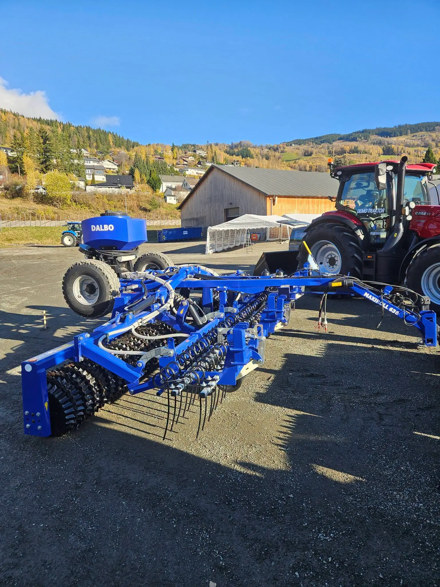 Blått DALBO-redskap for jordarbeiding utstilt foran en Case IH-traktor på Stavsmartn på Tretten.