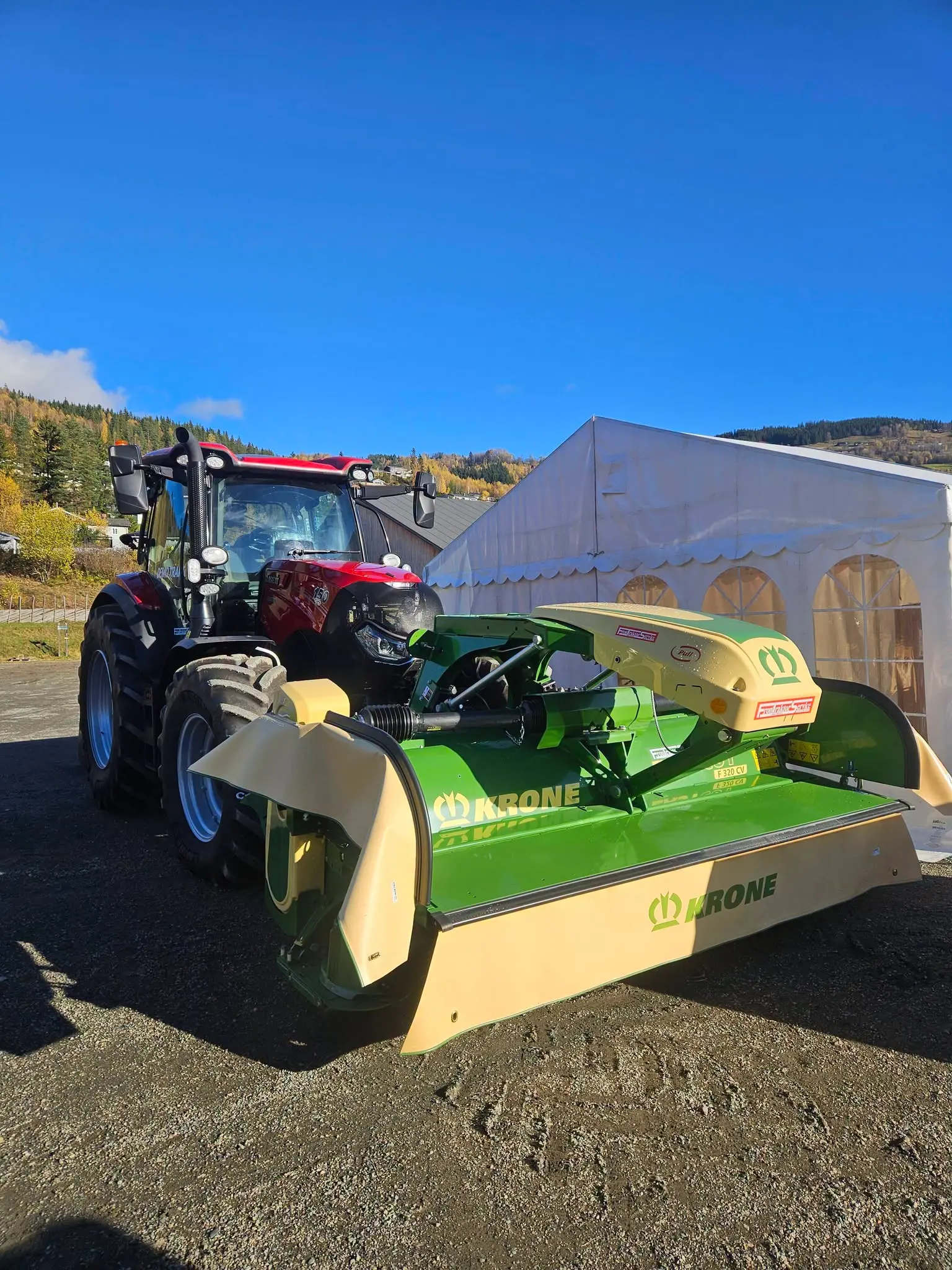 Grønn KRONE frontslåmaskin montert foran en Case IH-traktor på Stavsmartn på Tretten.
