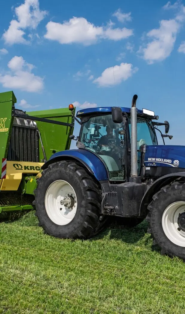New Holland T7.270 med KRONE ZX 430 GD lessevogn på nyslått eng under blå himmel med sommerskyer